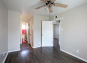 Thumbnail 11 of 34 - A room with a ceiling fan and wooden floors.