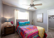Thumbnail 10 of 34 - A bedroom with a bed, nightstand, and a ceiling fan.