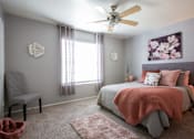 Thumbnail 9 of 34 - A bedroom with a bed, chair, and a ceiling fan.