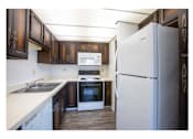 Thumbnail 29 of 36 - A kitchen with a white refrigerator and brown cabinets.