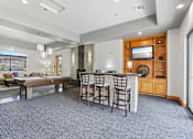 Thumbnail 14 of 27 - A spacious living room with a bar area and a television.