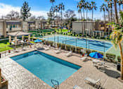 Thumbnail 2 of 16 - A pool surrounded by palm trees and a tennis court.