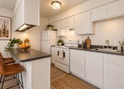 Thumbnail 5 of 45 - A kitchen with white cabinets and a black countertop.