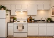Thumbnail 6 of 45 - A white kitchen with a stove top oven and a sink.