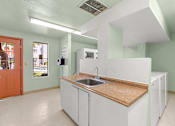 Thumbnail 40 of 42 - A kitchen with white cabinets and a wooden countertop.