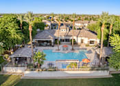Thumbnail 13 of 25 - A large house with a pool surrounded by palm trees.
