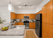Thumbnail 4 of 25 - A kitchen with wooden cabinets and a black refrigerator.