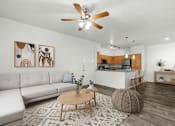Thumbnail 5 of 25 - A living room with a white sofa, a wooden coffee table, and a ceiling fan.