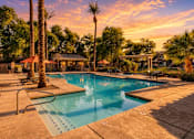 Thumbnail 1 of 25 - A pool surrounded by palm trees and a sunset sky.