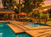 Thumbnail 2 of 25 - A pool with a slide and a patio area with a table and chairs.