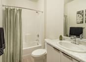 Thumbnail 7 of 12 - A bathroom with a toilet, sink, and shower curtain.