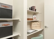 Thumbnail 12 of 12 - A white desk with a green chair and a white shelf with boxes and books.