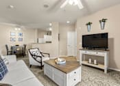 Thumbnail 19 of 23 - A living room with a white couch, a wooden coffee table, and a flat-screen TV mounted on the wall.