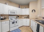 Thumbnail 18 of 23 - A kitchen with white cabinets and appliances.