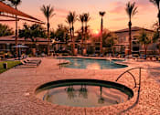 Thumbnail 2 of 23 - A swimming pool surrounded by palm trees at sunset.