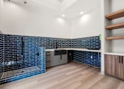 Thumbnail 45 of 52 - A modern kitchen with a blue tile backsplash and wooden flooring.