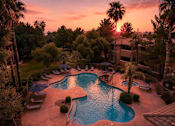 Thumbnail 3 of 19 - A beautiful sunset view of a pool surrounded by palm trees.