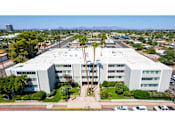 Thumbnail 8 of 36 - A large white building with a parking lot in front of it.