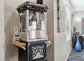 Thumbnail 11 of 16 - A hot buttered popcorn machine is on a table.