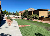Thumbnail 29 of 33 - A building with a brown roof and tan walls is surrounded by a grassy area and trees.