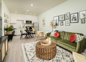 Thumbnail 2 of 12 - A living room with a green couch and a wicker table.