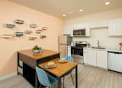 Thumbnail 9 of 12 - A kitchen with a table and chairs in the foreground and a refrigerator, oven, and microwave in the background.