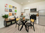 Thumbnail 3 of 12 - A kitchen with a table and chairs and a fridge.