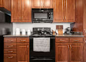 Thumbnail 4 of 52 - A kitchen with wooden cabinets and a black stove top oven.