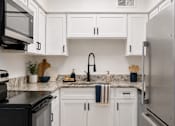 Thumbnail 1 of 25 - A kitchen with white cabinets and a black stove top oven.