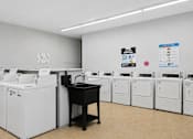 Thumbnail 22 of 25 - A room with a black desk and white washing machines.