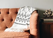 Thumbnail 2 of 27 - A living room with a couch, a chair, a coffee table, and a television.