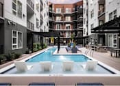 Thumbnail 5 of 28 - A pool surrounded by white chairs and buildings.