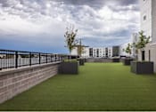 Thumbnail 10 of 28 - A grassy area with planters and a building in the background.