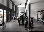 Thumbnail 11 of 28 - A gym with a variety of equipment including weights and a fan.