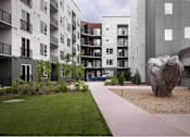 Thumbnail 9 of 28 - A large rock sits in the middle of a gravel area in front of a building.