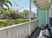 Thumbnail 5 of 38 - A balcony with a table and chairs overlooks a green yard.