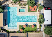 Thumbnail 41 of 45 - An aerial view of a pool surrounded by trees and a building.