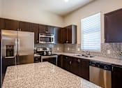 Thumbnail 5 of 45 - A kitchen with a granite counter top and stainless steel appliances.