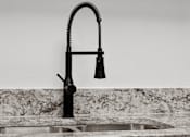 Thumbnail 7 of 25 - A black kitchen faucet with a pull-down sprayer is installed over a sink.