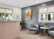 Thumbnail 16 of 25 - A reception area with a wooden desk, two chairs, and a painting on the wall.
