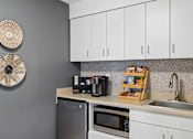 Thumbnail 17 of 25 - A kitchen with a microwave, refrigerator, and sink.