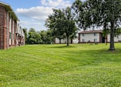 Thumbnail 25 of 25 - A grassy field with trees and apartment buildings in the background.