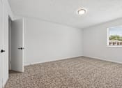 Thumbnail 12 of 25 - A room with a carpeted floor and a window showing a view of a house.