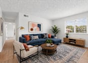 Thumbnail 2 of 25 - A living room with a blue couch and a painting on the wall.