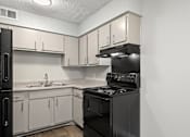 Thumbnail 3 of 26 - A black stove in a kitchen with white cabinets.