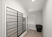 Thumbnail 20 of 26 - A room with a wall of mailboxes and a trash can.