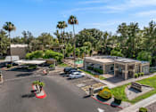 Thumbnail 16 of 17 - A parking lot with a building and palm trees in the background.