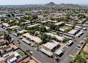 Thumbnail 17 of 17 - A large parking lot is surrounded by buildings and trees.