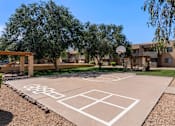 Thumbnail 11 of 17 - A basketball court is located in a courtyard surrounded by trees and buildings.