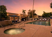 Thumbnail 2 of 17 - A pool with a hot tub and a building in the background.